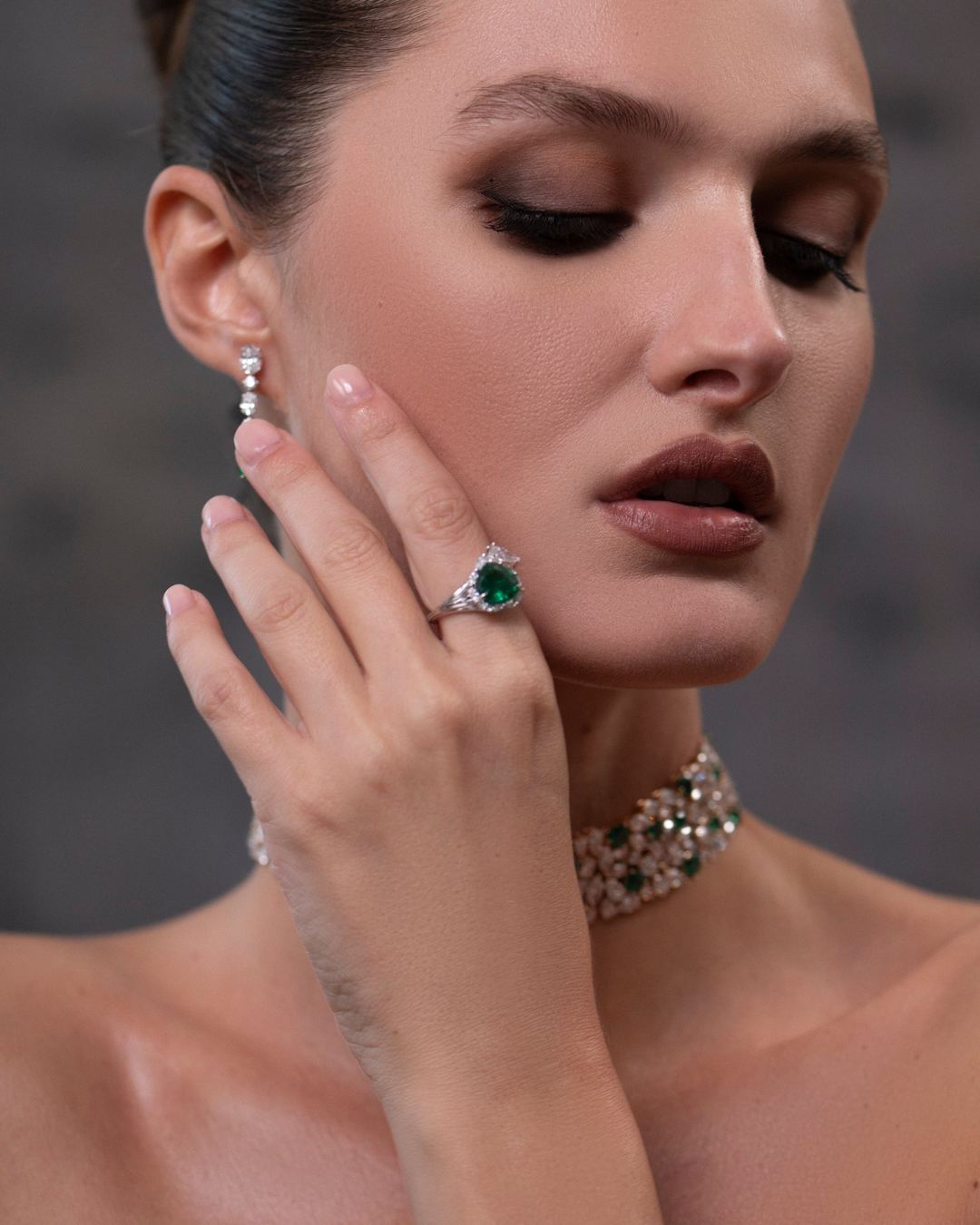 Un anello con smeraldo e un collier di diamanti, indossati