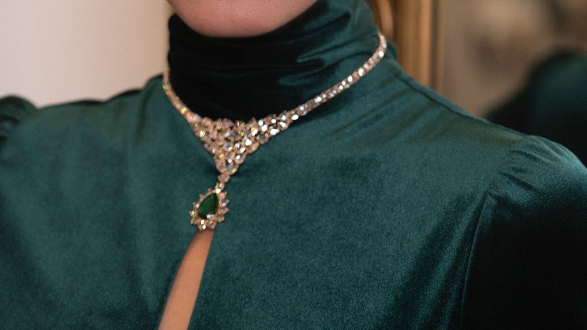 Una collana di diamanti con smeraldo su un abito di velluto verde